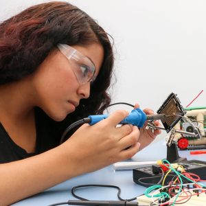 young lady performing electrical repair to a circuit board