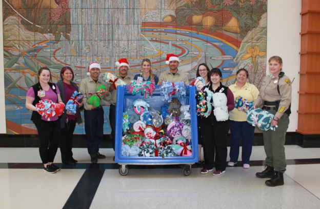 UC Davis Children's Hospital staff, Pine Grove YCF youth and DJJ staff pose with dozens of comfort blanket kits put together by youth for distribution to patients and families.