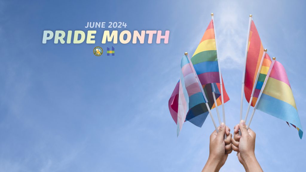 Pride Month June with two hands holding rainbow flags