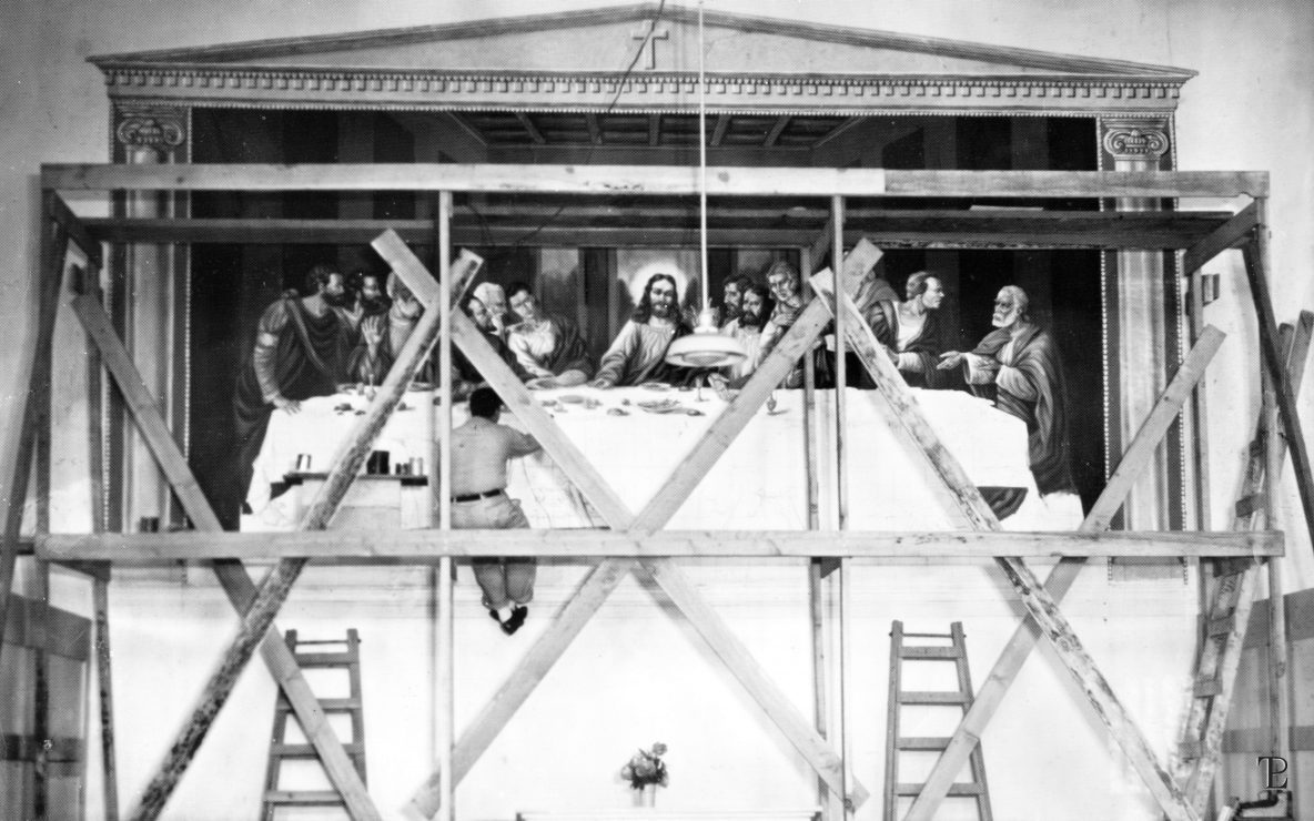 Artist Ralph Pecor sits on scaffolding while he paints at mural on a church wall at Folsom State Prison in 1938.