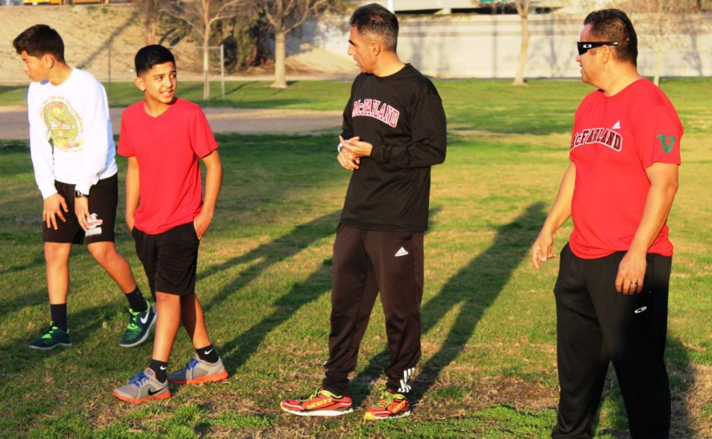 Two CDCR staff members coach a youth running team in McFarland. 