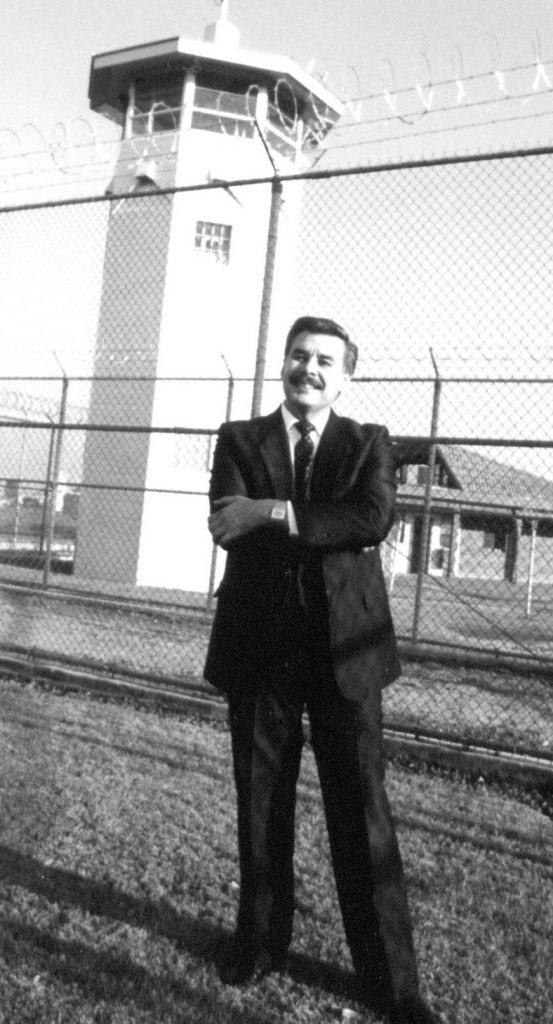 Man with prison tower behind him.