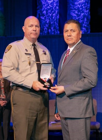 Greg Caravas receives 2018 Medal of Valor from Secretary Ralph Diaz.