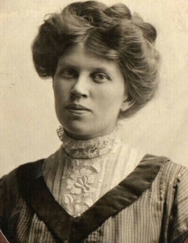 Woman wearing early 1900s clothing and hairstyle.