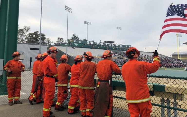 Pine Grove Youth Conservation Camp crew members prepare to walk out onto the field during the 2019 Guns and Hoses Pig Bowl charity game.