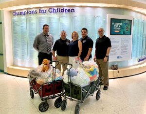Five Avenal prison staff stand in front of two wagons full of toys for sick children in a hospital.
