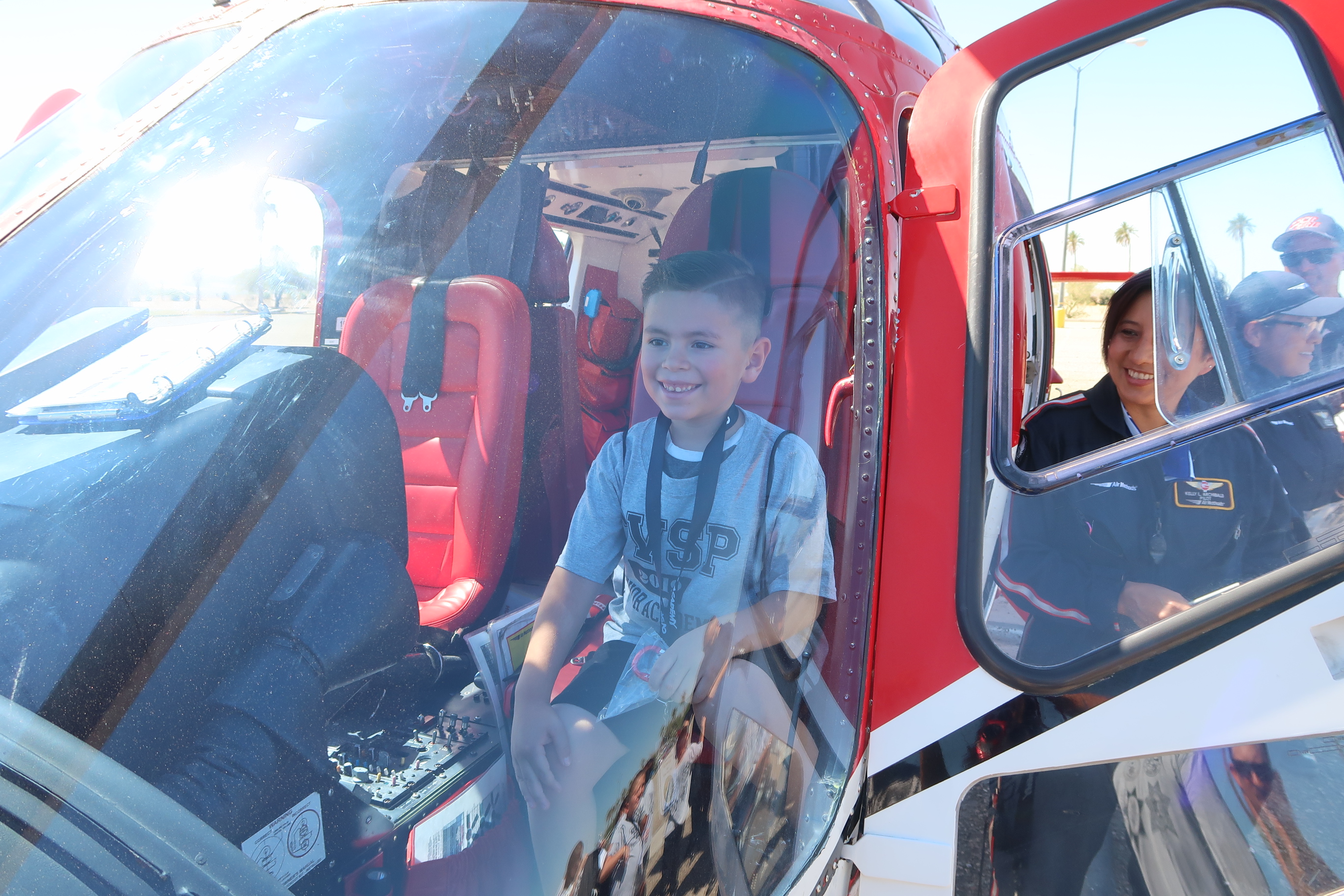 Smiling young boy sits in helicopter seat.