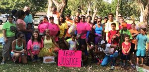Twenty people facing camera with a sign with the words Team Justice