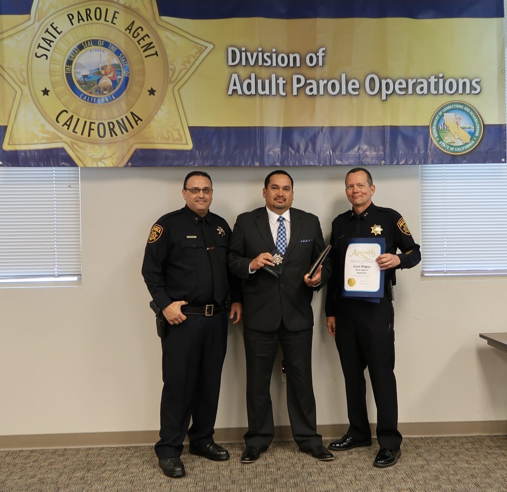 Three men stand in front of a banner that says Division of Adult Parole Operations.