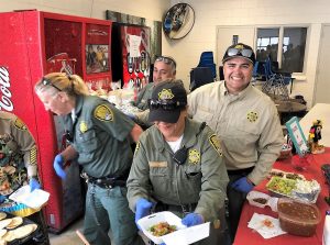 People in uniform load up tacos.