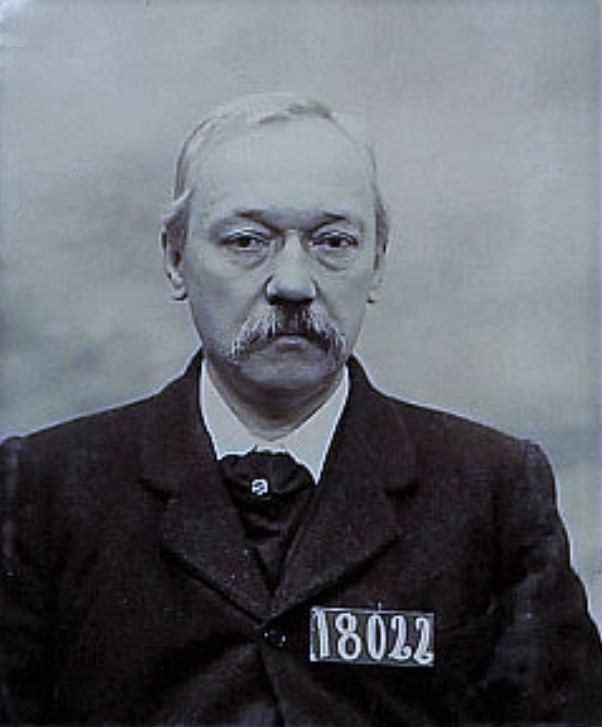 Older man in coat and tie with number 18022 on his chest. 