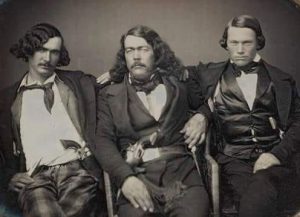 Three men in old western clothing.