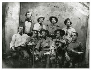 Men with shovels and dirty clothing pose for a photo.