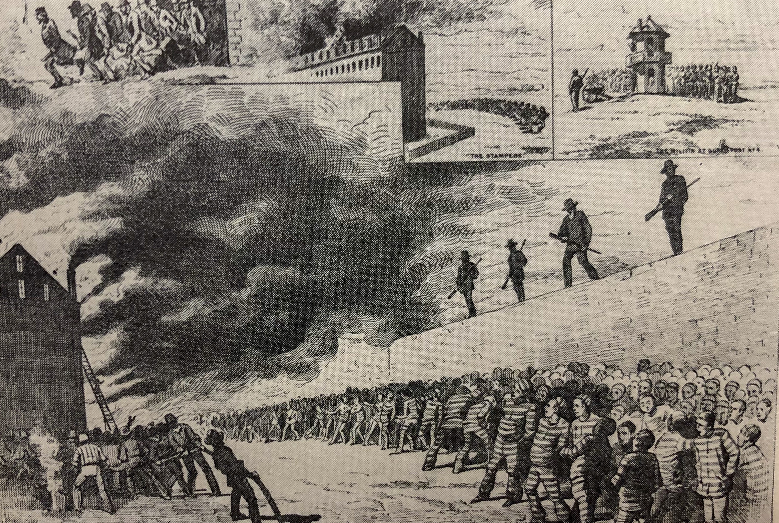 Men in uniform stand atop a wall while men in striped outfits back away from smoke.