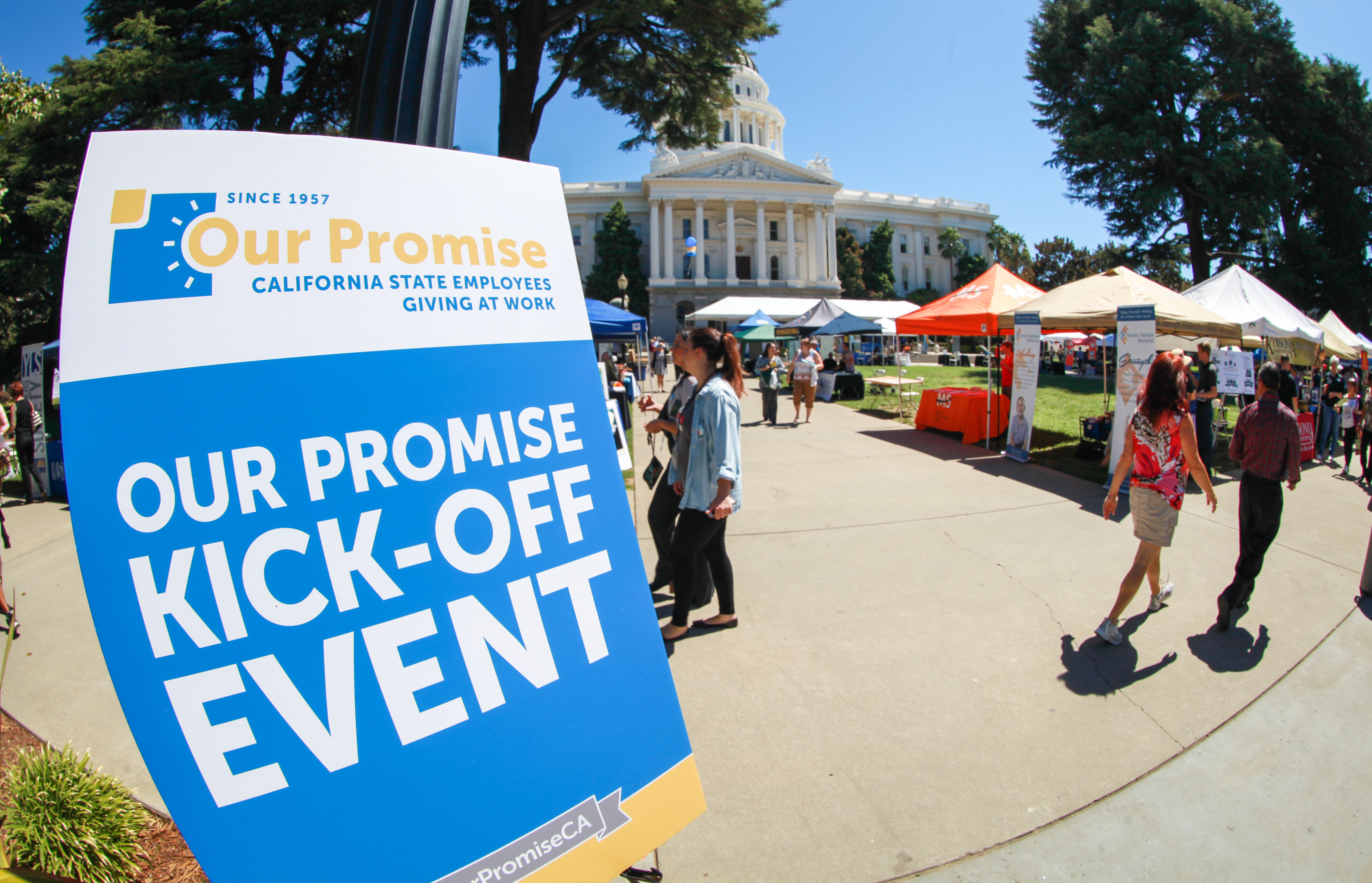 Sign says Our Promise Kick-Off Event while people walk around at the state capitol.