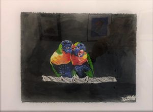 Red, green and blue birds cuddle on a branch.