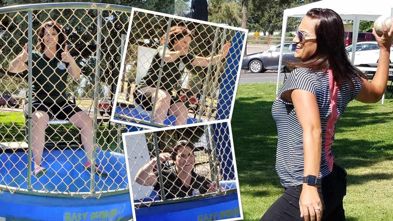 Woman throws softball at a dunk tank, as another woman drops into the water.