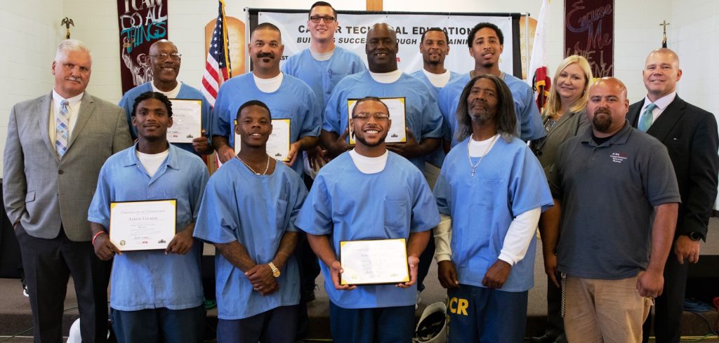Fourteen people facing the camera. Some hold graduation certificates