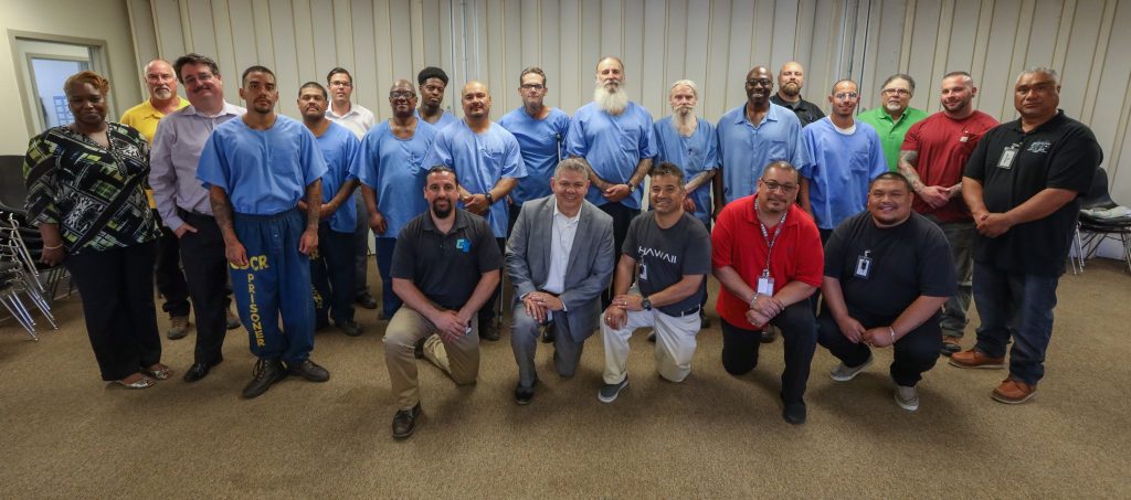 Inmates stand behind prison staff members.