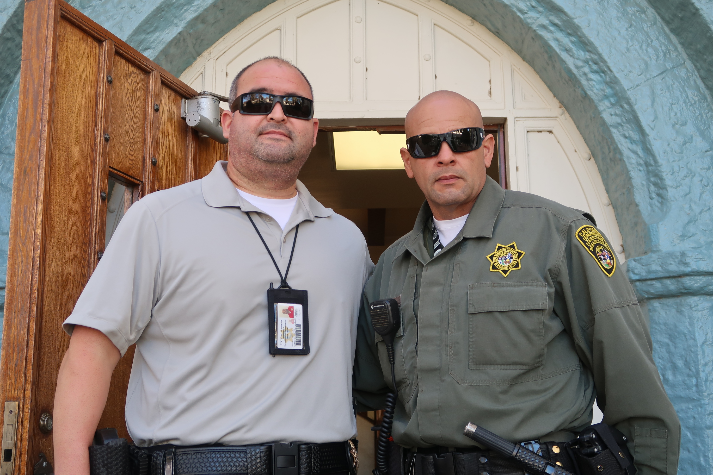 A man in uniform stands beside another man who is wearing a lanyard.