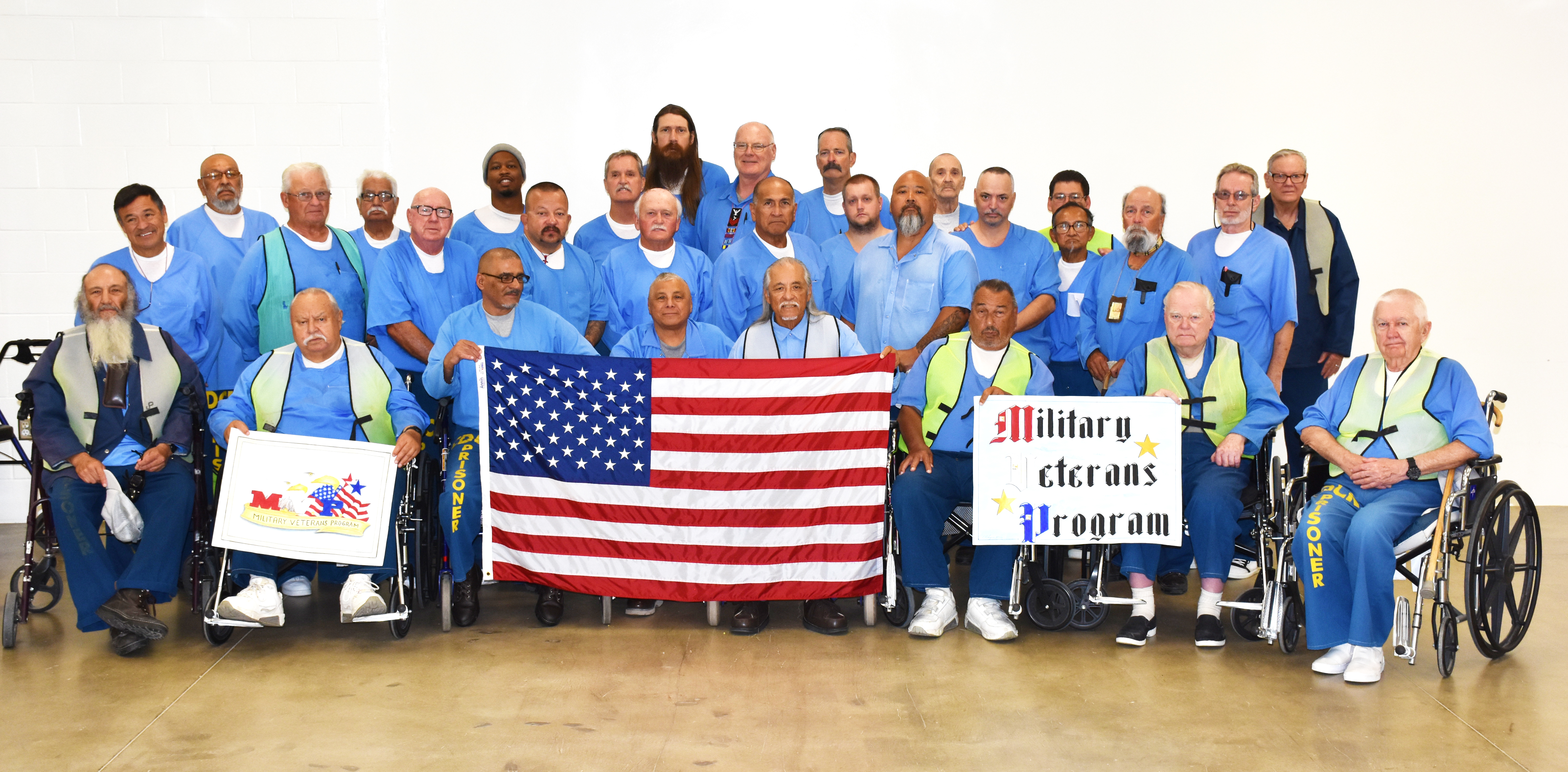 Inmates in blue shirts hold a U.S. flag.