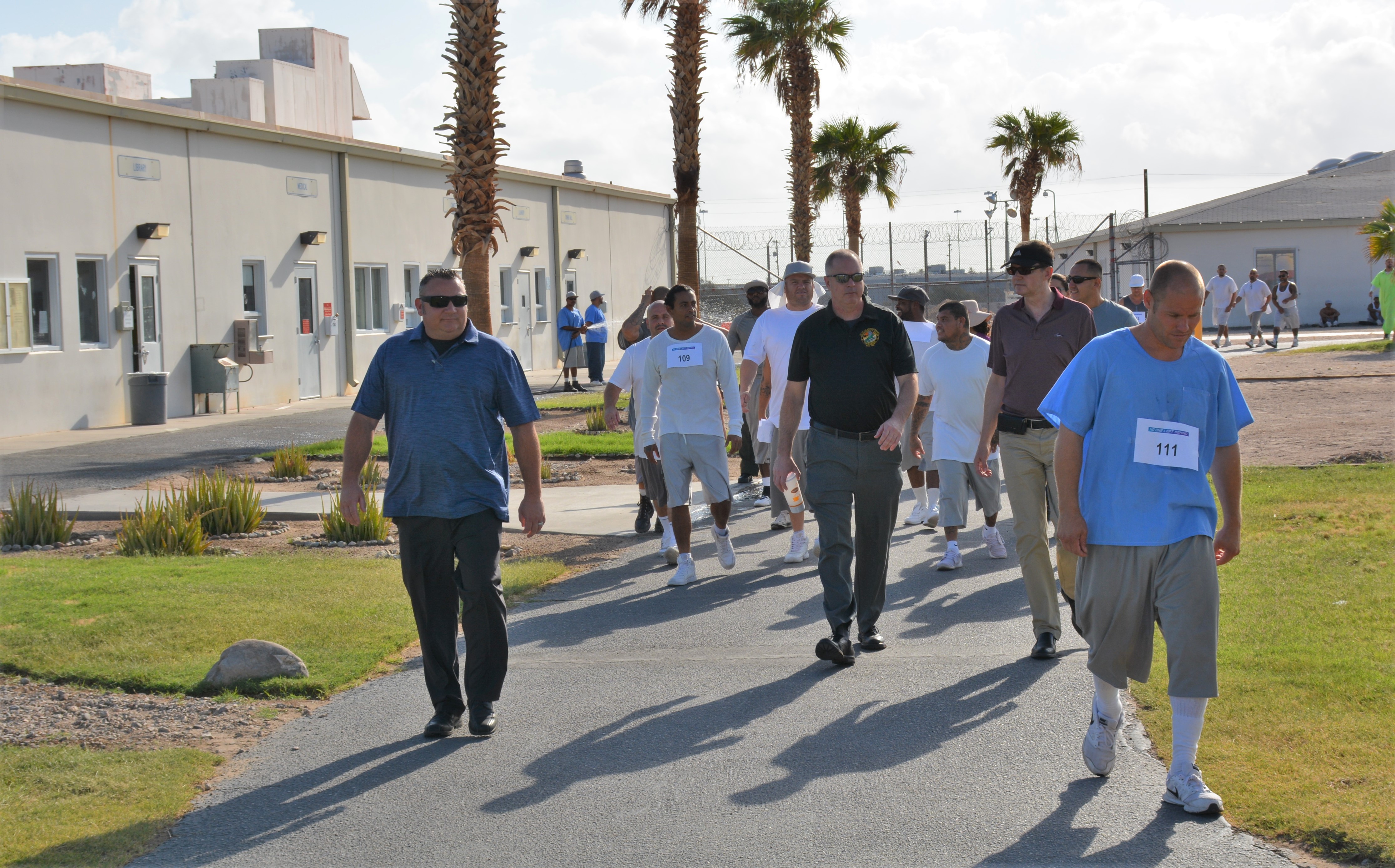 Men walk along a path inside a prison.