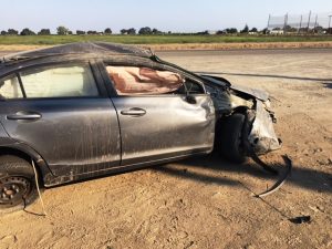 Smashed car sits in field.