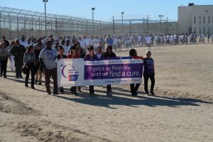 People walk a track while holding a Relay for Life banner.