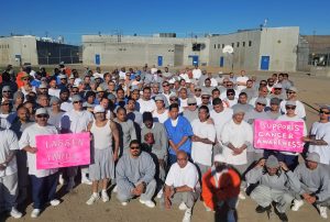 Men in a prison hold pink signs.