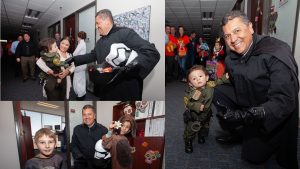 Mann in a Star Wars costume passes out candy to costumed children and their parents.