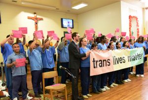 Group of people standing and holding sign that states trans lives matter
