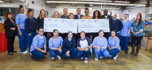 Female inmates and others pose with large oversized checks.