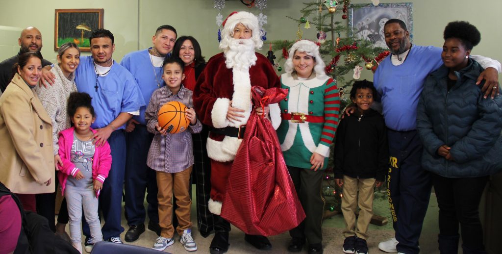 Prison inmates and their family visitors pose for a photo with Santa and Mrs. Claus.