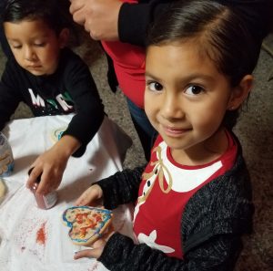 Smiling child holds a cookie she decorated.