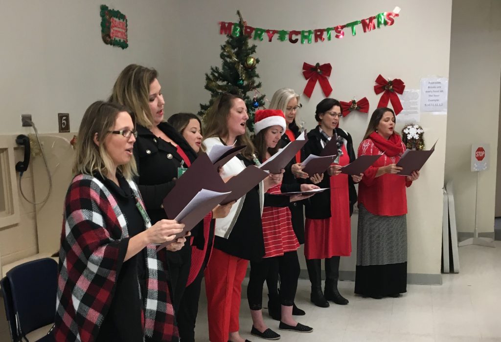 Women hold lyric sheets while singing Christmas carols in a prison.