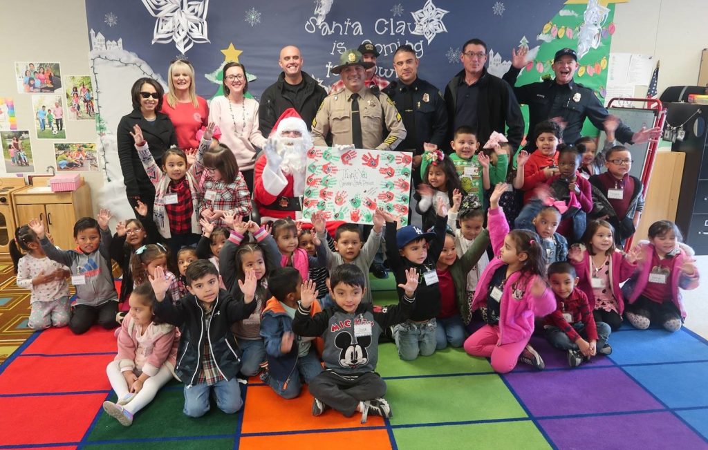 Santa and correctional staff are surrounded by young children.