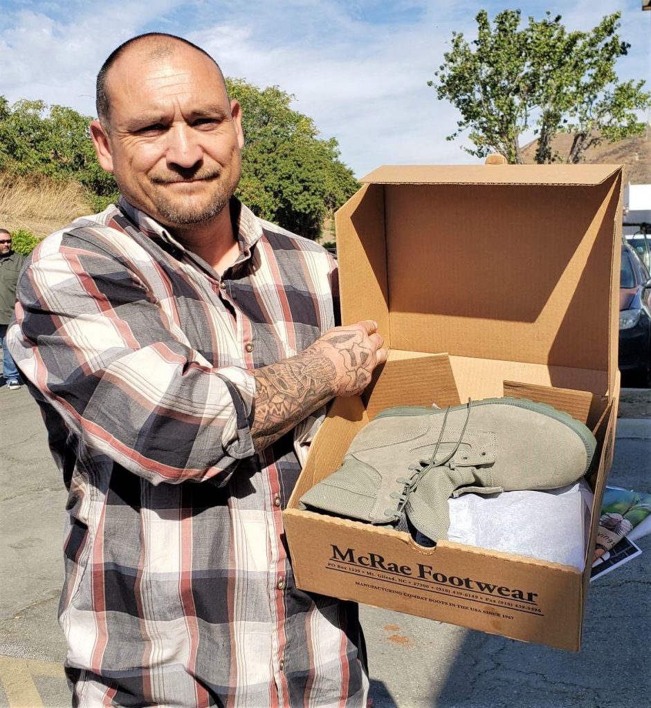 A man holds a box with a boot it in.