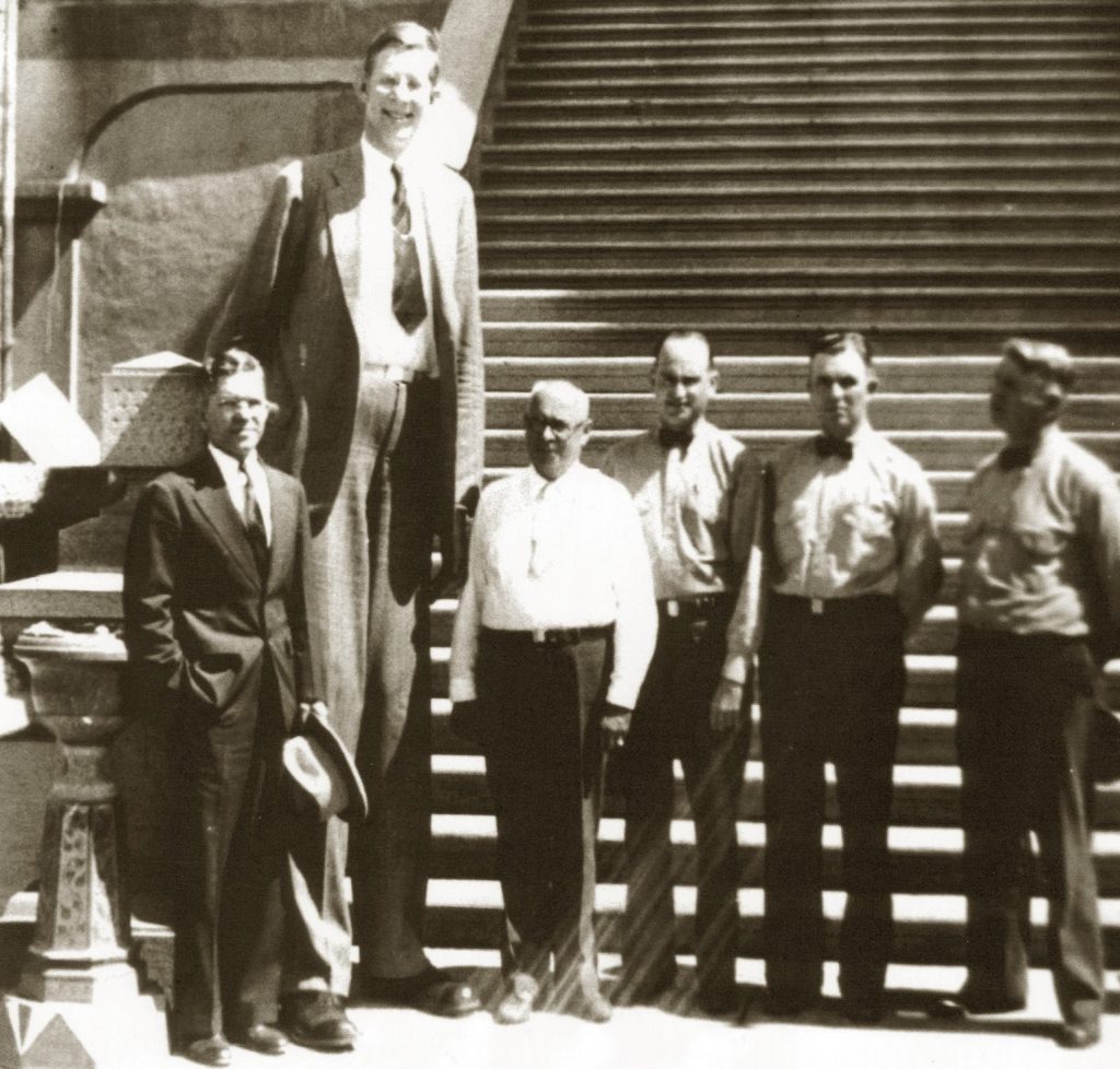 Robert Wadlow towers over five other people in front of Folsom prison.