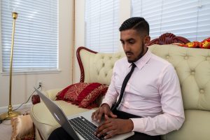 Man sits on couch with laptop computer.