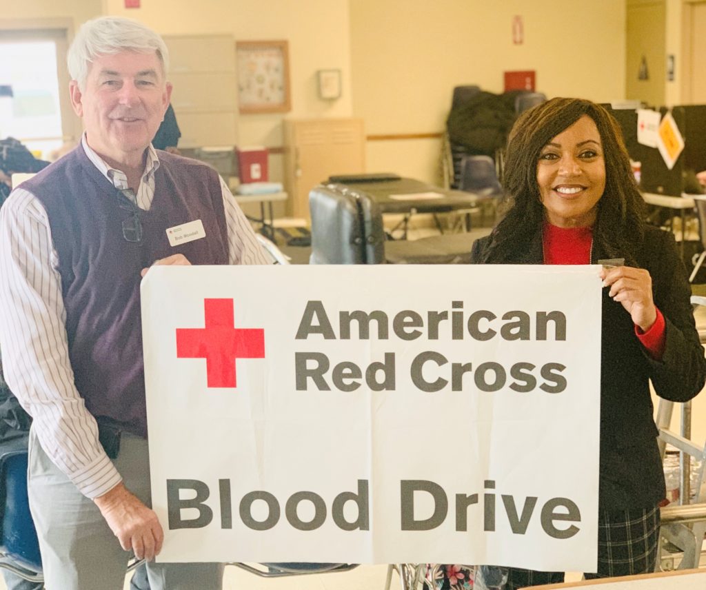 Red Cross blood drive banner held by a man and a woman in a prison.