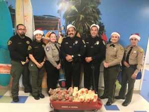 Officers pose with a box full of teddy bears.