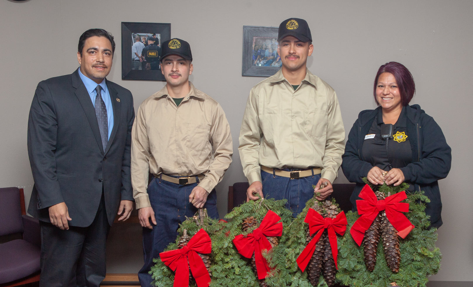 Two fire camp youth hold wreaths while a parole agent and the CDCR executive stand on either side.