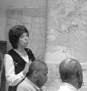 Folsom Prison teacher Linda Nielsen stands in front of a wall map.