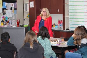Woman wearing a visitor badge speaks to kids.