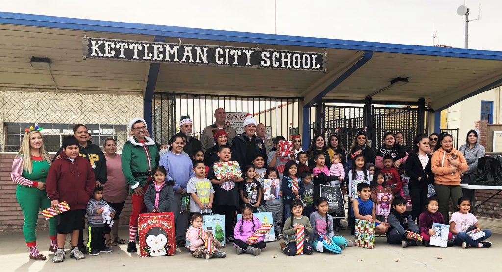 Correctional staff pose at Kettleman City School with kids and other volunteers.