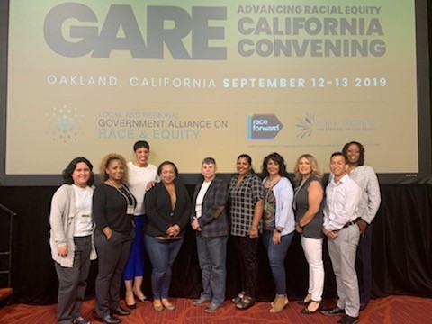 People stand under a screen that says GARE California Convention.