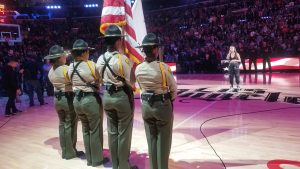 Female officers stand at attention while holding flags.