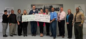 Inmates, staff and volunteers at Kern Valley State Prison hold two oversize checks.