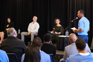 A prison inmate speaks into a microphone with others listen.