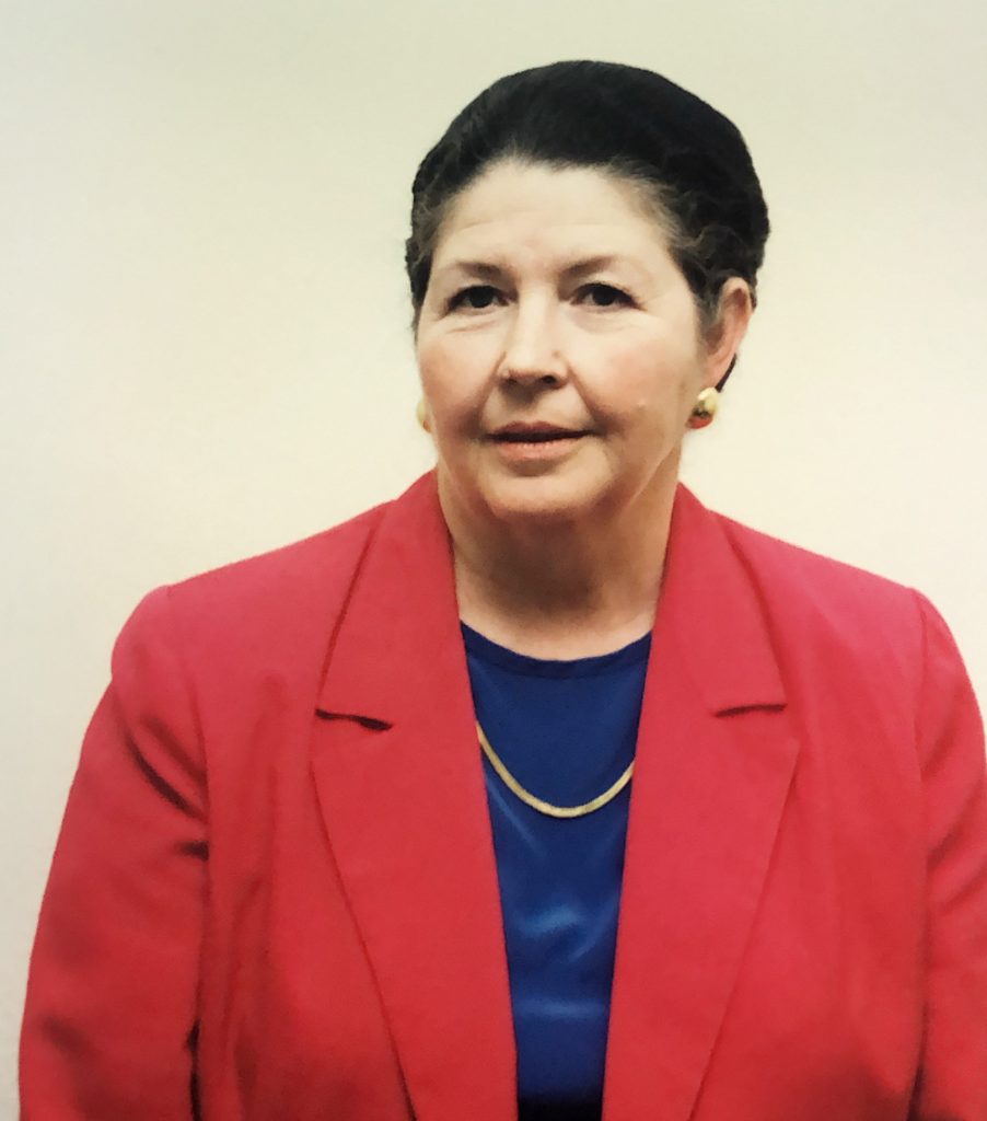 Woman wearing red jacket and blue blouse.